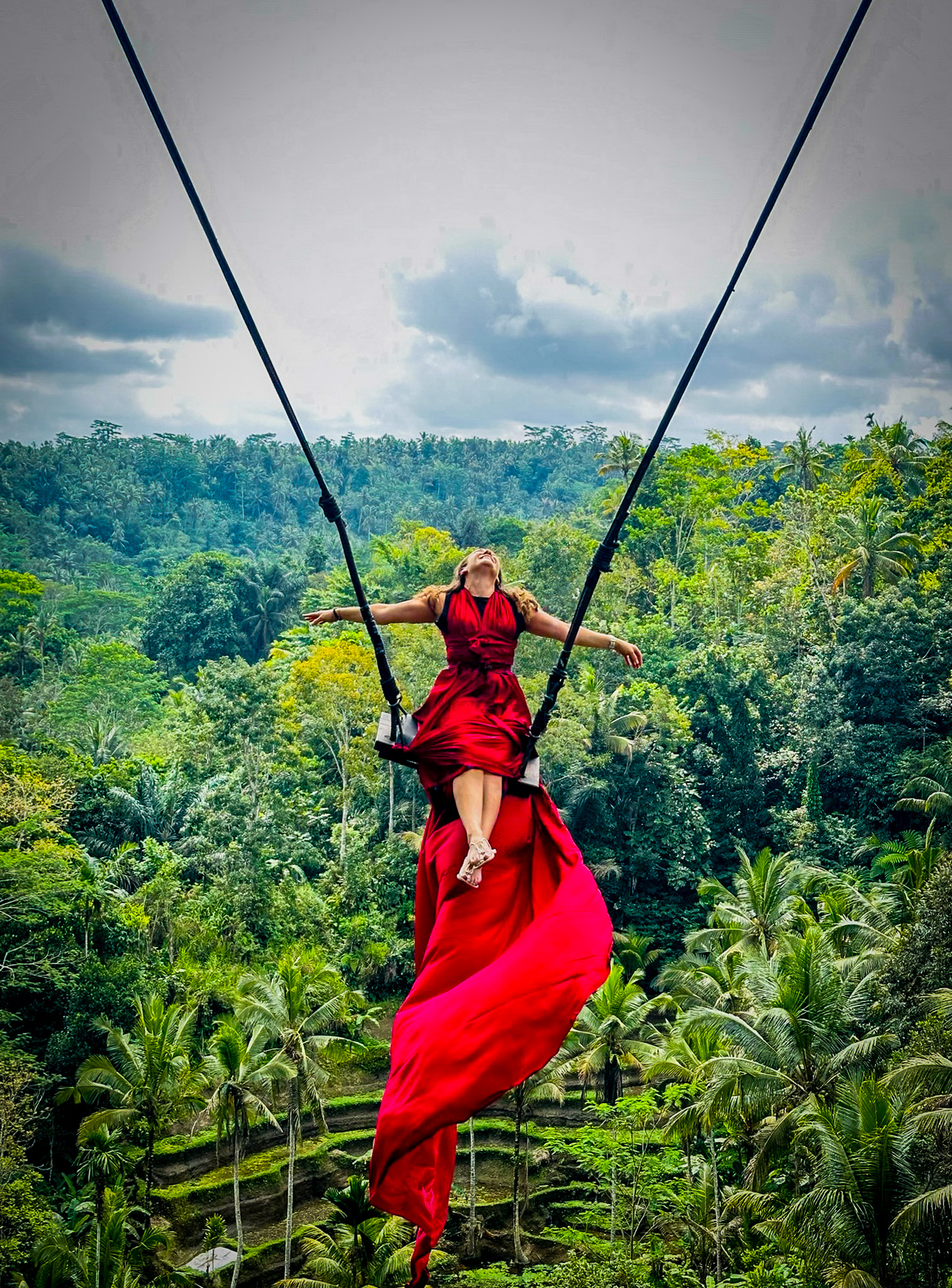 Woman in swing in Bali wearing long flowing red dress