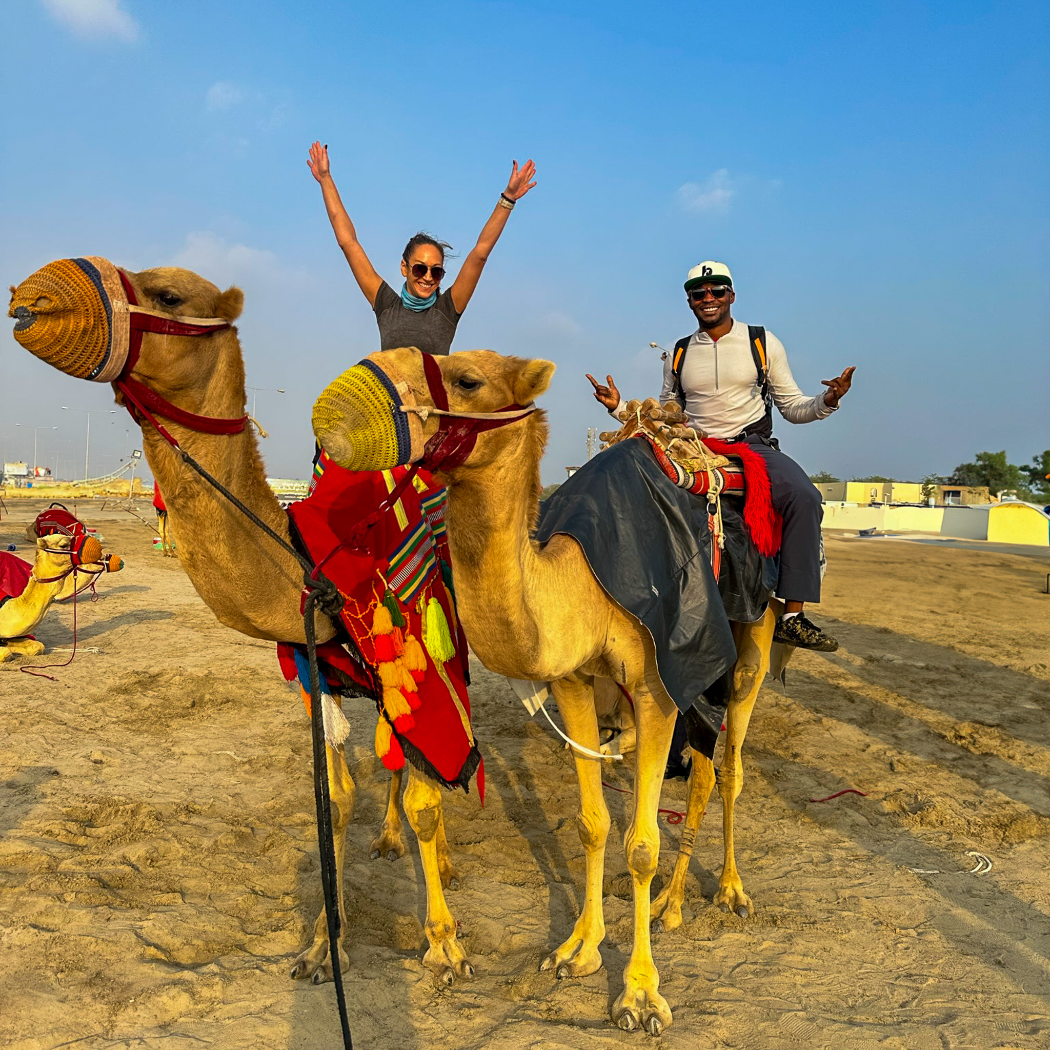 man and woman on 2 separate camels in desert