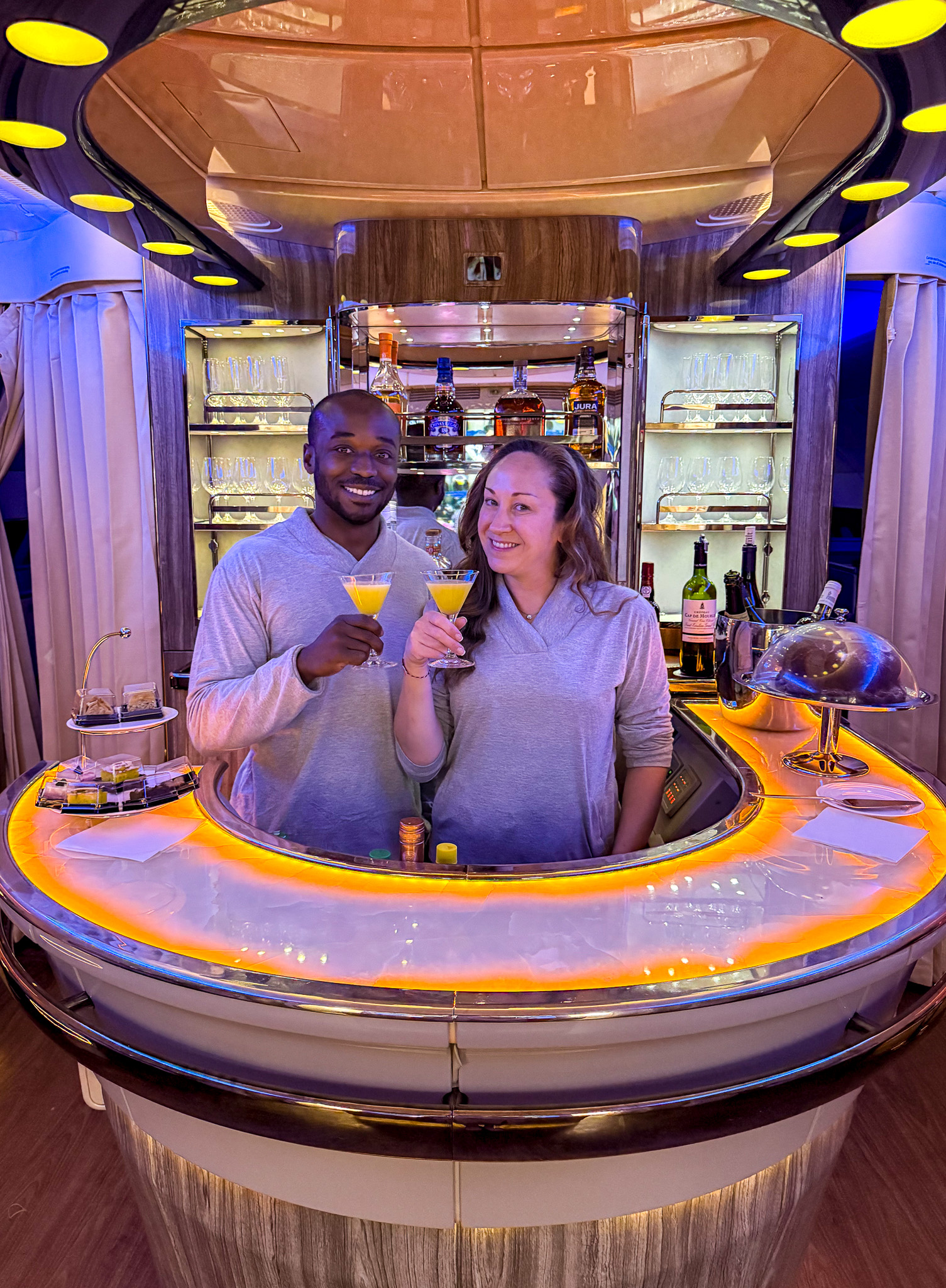 two people enjoying martinis behind a bar on an airplane