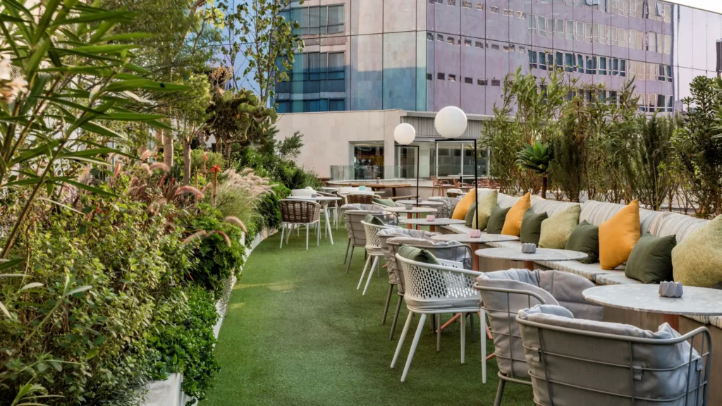 A serene and stylish outdoor terrace at Andaz Mexico City, featuring lush greenery, modern seating with plush cushions, and a vibrant ambiance for relaxation.