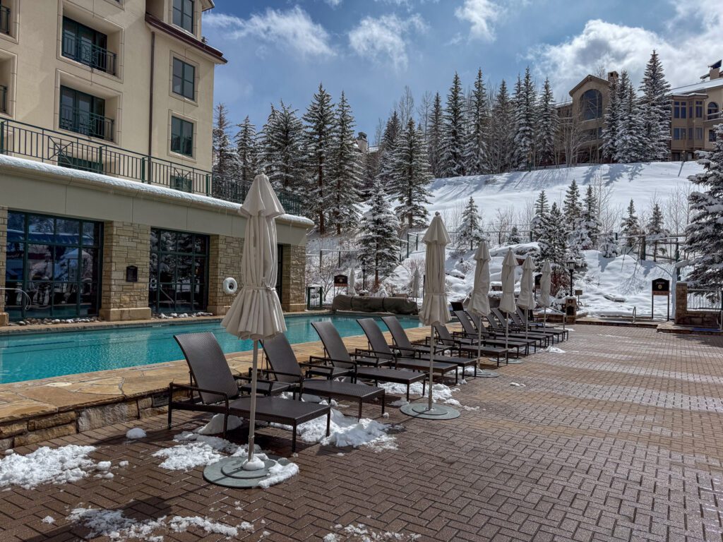 Heated outdoor lap pool and sun loungers surrounded by snow-covered trees at Park Hyatt Beaver Creek