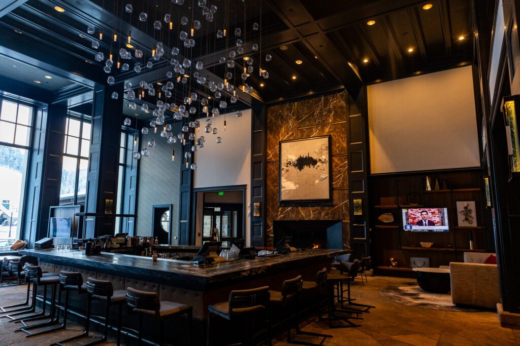 Modern, stylish bar and lounge area at Park Hyatt Beaver Creek with high ceilings and hanging lights