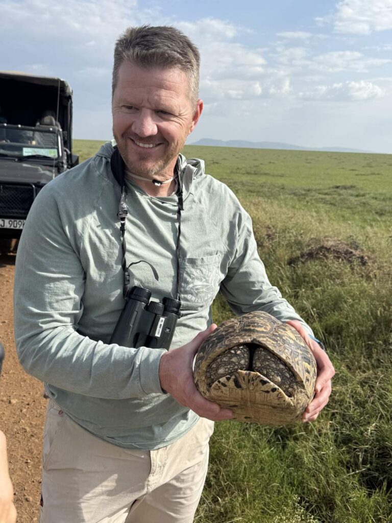 Safari guest holding a tortoise during a guided wildlife experience in the Masai Mara near JW Marriott Lodge.