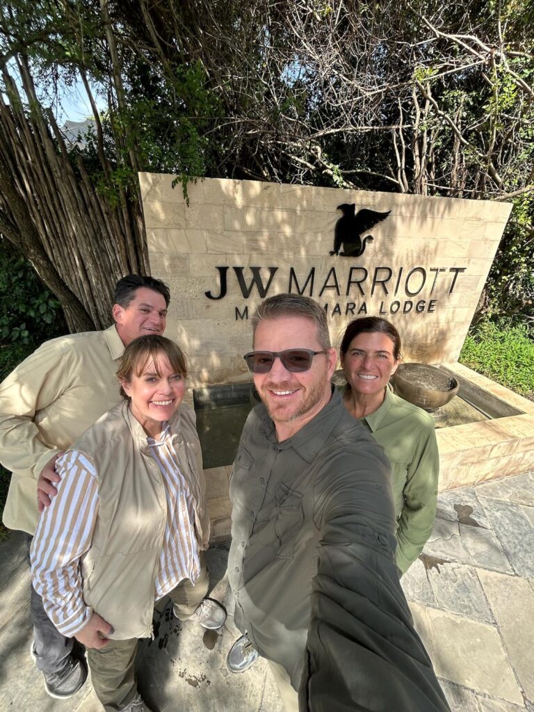 Guests posing in front of JW Marriott Masai Mara Lodge sign in Kenya