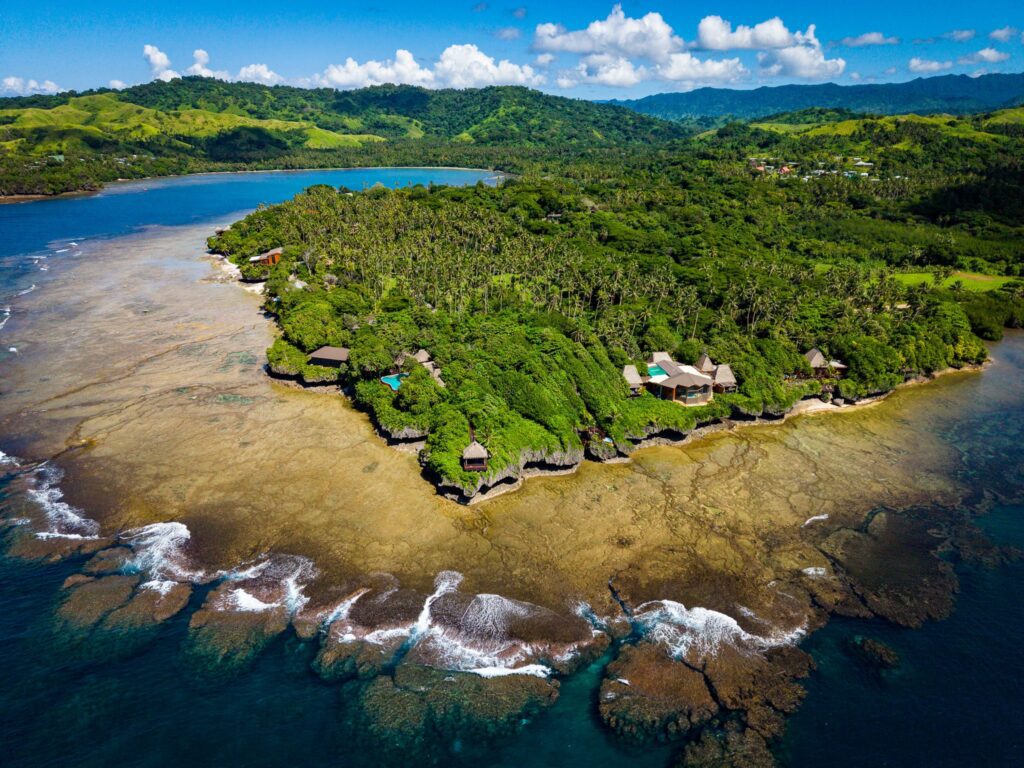 Drone aerial view of Namale Resort & Spa on a lush private peninsula in Fiji surrounded by turquoise ocean and coral reef.