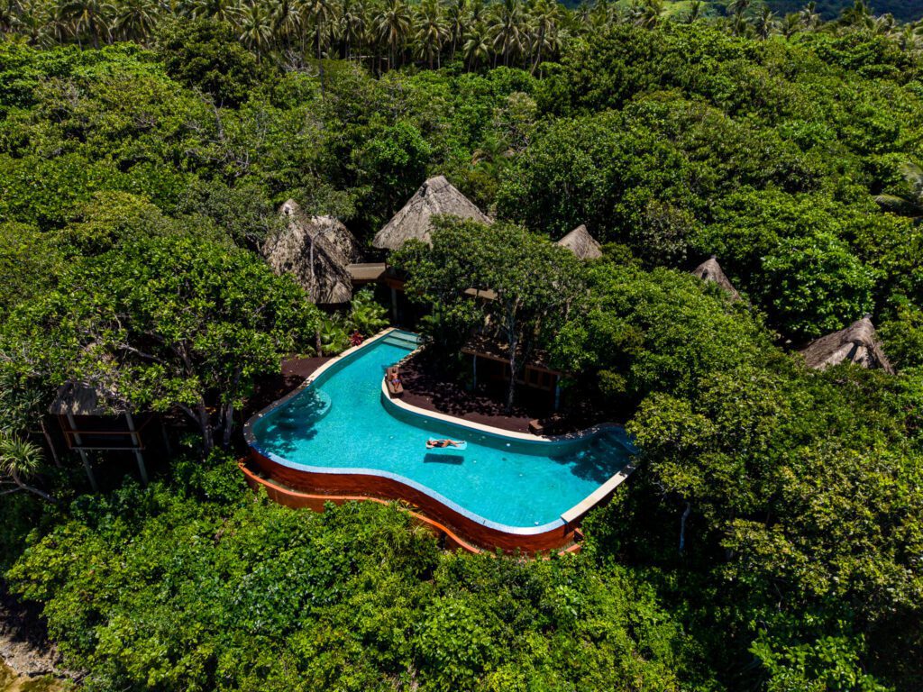 Large infinity pool surrounded by lush tropical jungle at Namale Resort & Spa, an adults-only all-inclusive in Fiji.