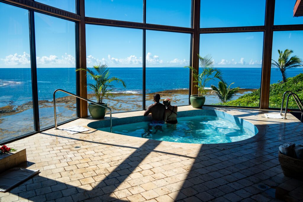 Couple relaxing in an oceanfront hydrotherapy pool at Namale Resort & Spa overlooking the Pacific in Fiji.