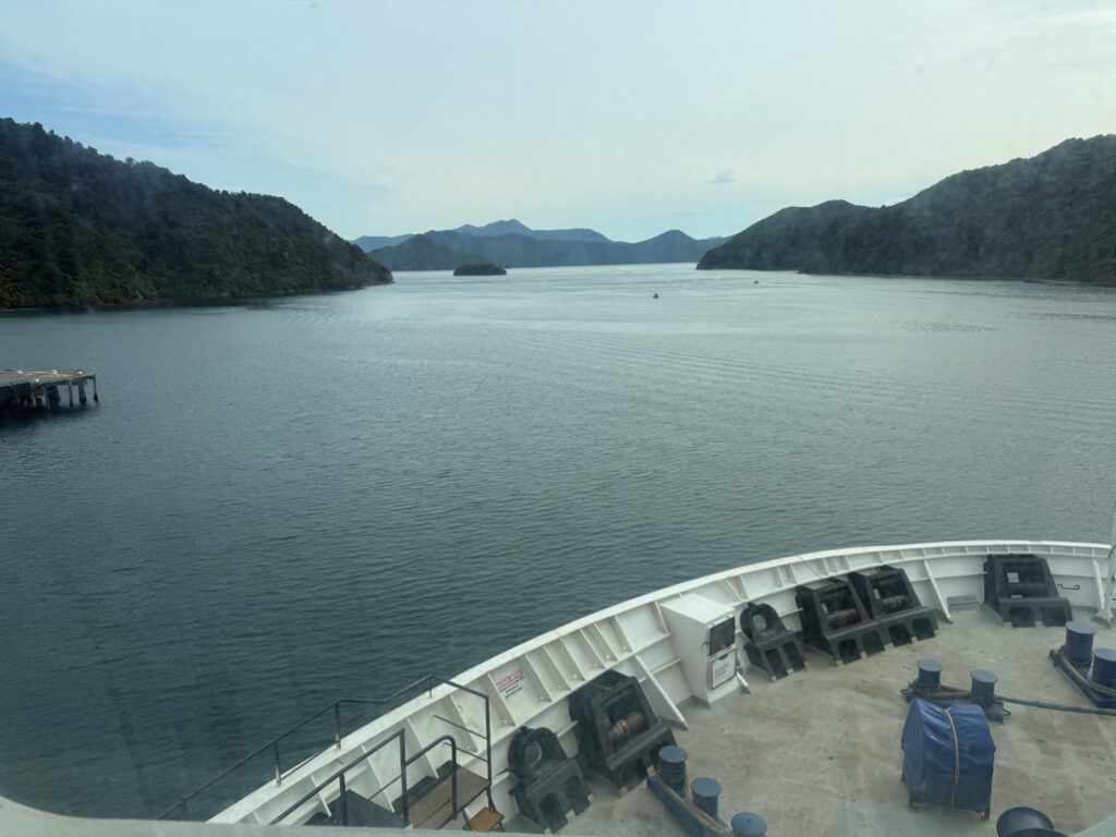View over the Interislander ferry’s bow toward the forested hills and calm waters of the Marlborough Sounds.