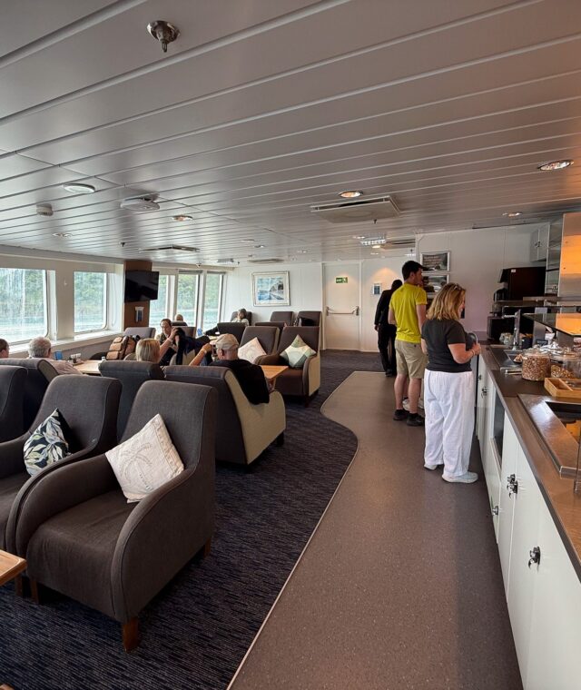 Interior of the Interislander Premium Lounge with armchair seating, large windows and a self-service food buffet.