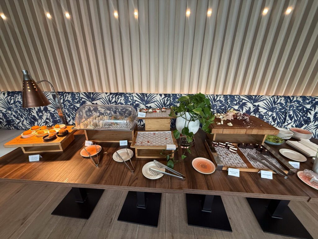 Breakfast buffet with pastries, bread, sliced fruit, and covered serving dishes