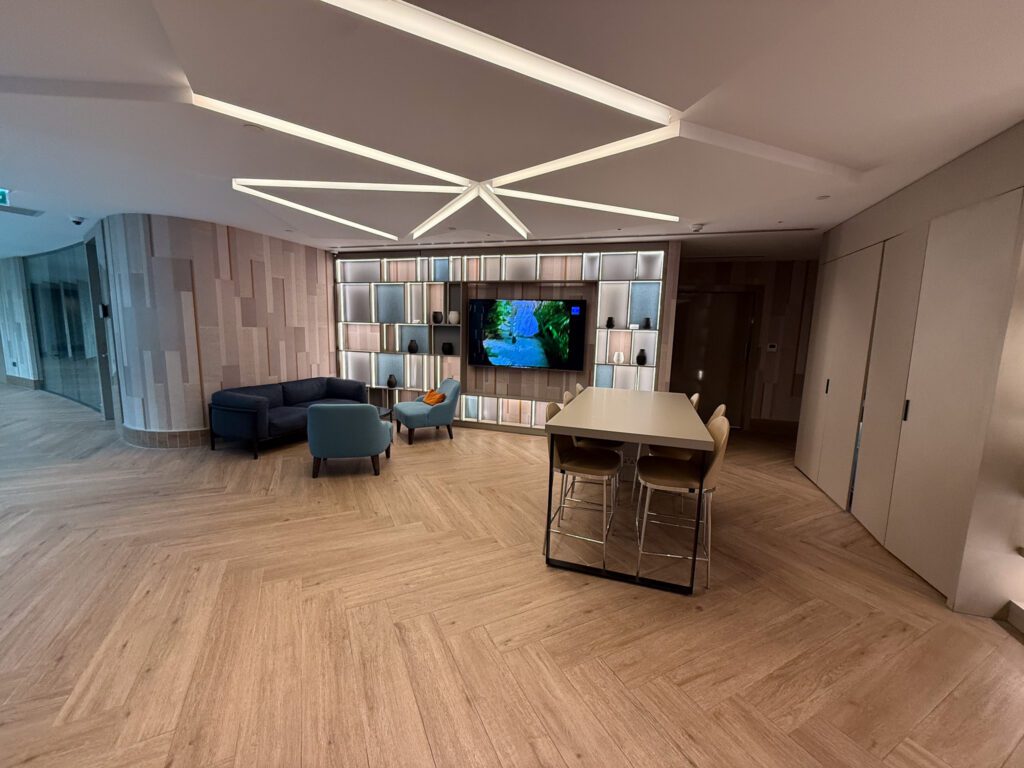 Regency Club lounge with sofas, a television, communal table, and geometric ceiling lights
