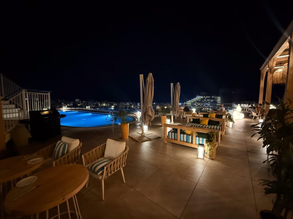 Illuminated rooftop pool and terrace seating at Hyatt Regency Malta at night