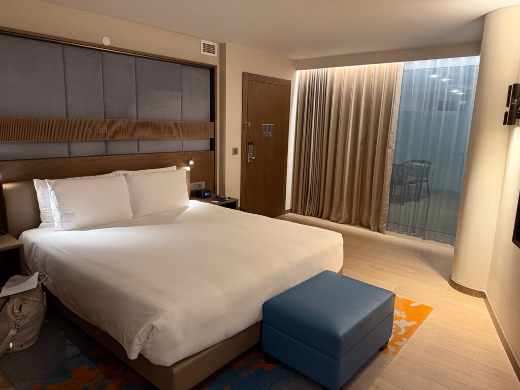 Suite bedroom at Hyatt Regency Malta with a king bed, upholstered bench, and balcony doors