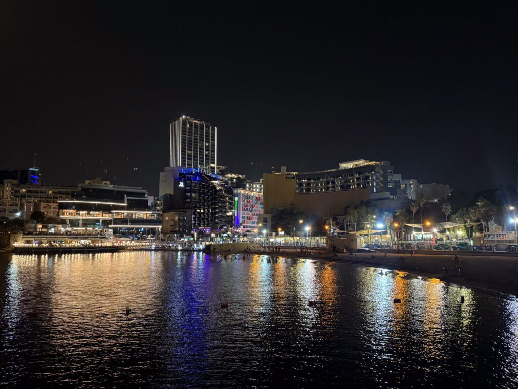 Night view across St. George’s Bay in St. Julian’s, Malta, with illuminated hotels reflected on the water