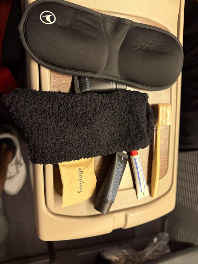 Eye mask, socks, earplugs, dental items and Lanvin toiletries arranged on the seat console.